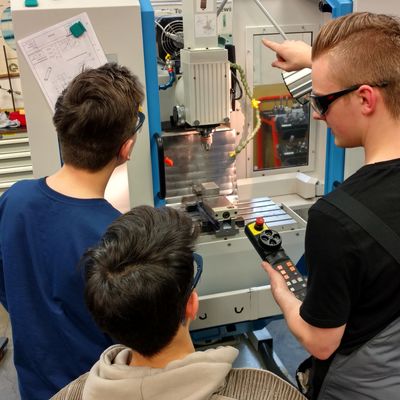 Simon Weyandt, ein Auszubildender zum Industriemechaniker im 1. Lehrjahr, zeigt den interessierten Achtkl�sslern, wie man mit einer Maschine fr�sen kann. Die Steuerung wird hier mit einer Fernbedienung vorgenommen.