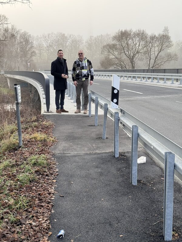Landrat Andreas M�ller (l.) und Ortsvorsteher Kai-Uwe Jochims auf der Ederbr�cke, die jetzt hinter der Leitplanke passiert werden kann. Der entsprechende Zuweg wurde befestigt und asphaltiert.