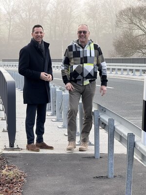 Landrat Andreas M�ller (l.) und Ortsvorsteher Kai-Uwe Jochims auf der Ederbr�cke, die jetzt hinter der Leitplanke passiert werden kann. Der entsprechende Zuweg wurde befestigt und asphaltiert.