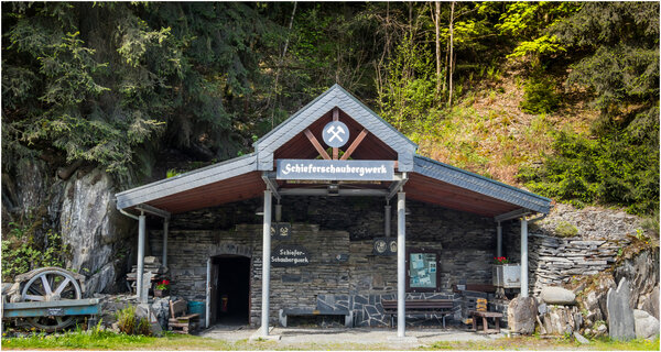 Au�enbereich vom Schieferschaubergwerk Raumland, mit Dach, Wald im Hintergrund.