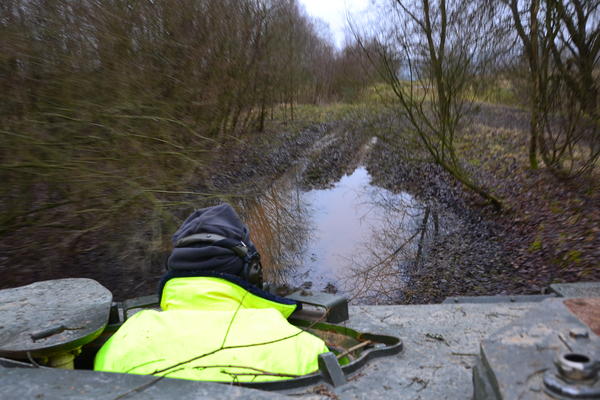 Der Blick vom Panzer auf eine gro�e Mulde gef�llt mit Wasser. Im Hintergrund B�ume und Geb�sch.