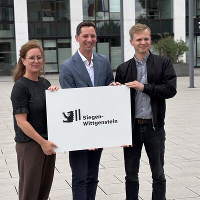 Yvonne M�ller (KD1), Landrat Andreas M�ller und Jakob Schneider (KD1) pr�sentieren das neue Logo des Kreises Siegen-Wittgenstein.