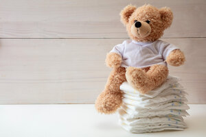 Baby diapers stack and teddy on white color floor